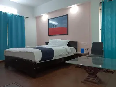 a bedroom with a bed and a desk with a laptop at Savi's home stay in Ooty