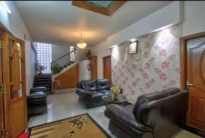 a living room with leather furniture and a staircase at Savi's home stay in Ooty