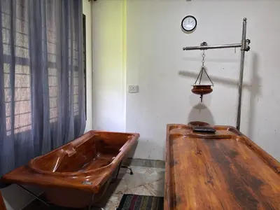 a wooden tub in a room with a clock on the wall at Aptha Ayurveda in Kadikkād