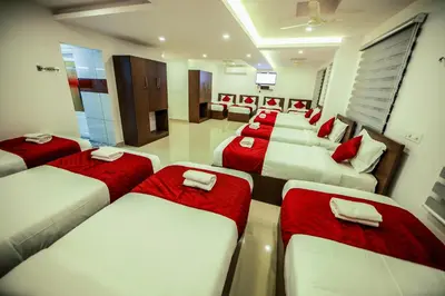 a room with a row of beds with red pillows at Airport Avenue Plaza in Nedumbassery