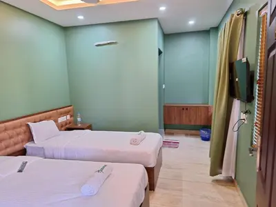 a room with two beds and a flat screen tv at Hamsted in Kottakkal