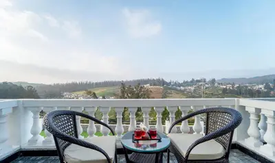 a balcony with two chairs and a table with wine bottles at Treebo Skydale Premium Suites, 1500 Mtrs From Ooty Lake in Ooty