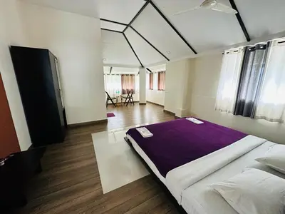 a bedroom with a large bed with purple sheets at Western Ghats Holiday Home in Kalpetta