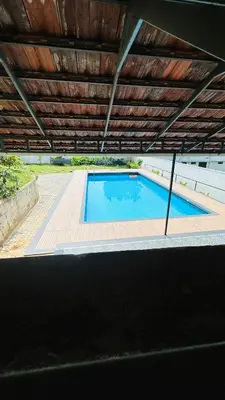 a large swimming pool with a wooden roof at Western Ghats Holiday Home in Kalpetta