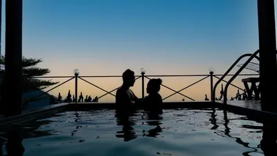 a couple sitting in a swimming pool with a roller coaster at Vayalada View Point Resort in Kozhikode