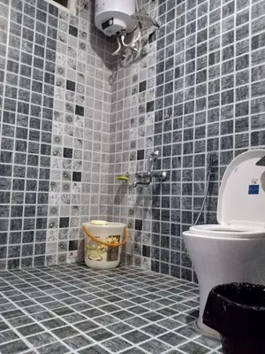 a bathroom with a toilet and blue tiled walls at Pear Tree Entire 2BHK Villa Kotagiri in Kotagiri