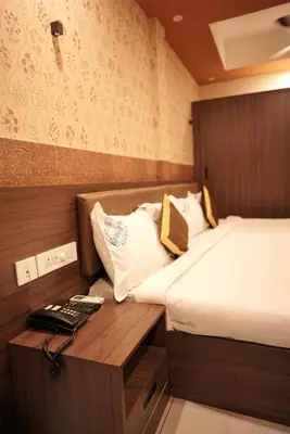 a small room with a bed and a desk with a phone at Kovilakam Achutham in Guruvāyūr