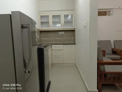 a small kitchen with a refrigerator and some chairs at Platinum Airport Lounge by VVP in Nedumbassery