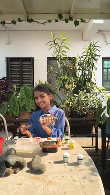 a young girl sitting at a table with plants at Arasu Homestay in Antarasante