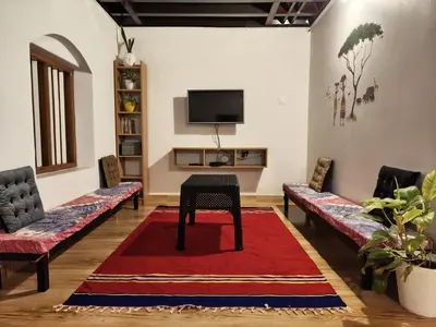 a living room with couches and a table on a red rug at Aadhya Homestay 4BHK in Wayanad