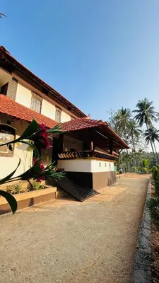a building with a staircase leading to a building with palm trees at Aadhya Homestay 4BHK in Wayanad
