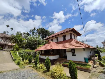 a house with a tiled roof in a yard at Aadhya Homestay 4BHK in Wayanad