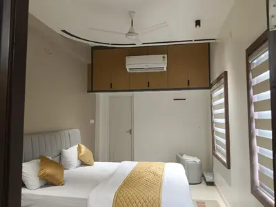 a bedroom with a bed with white sheets and gold pillows at Thulasi Avenue Inn in Pollāchi