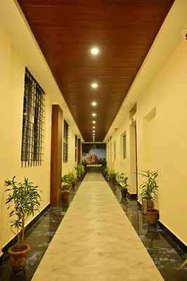 a hallway with potted plants and a wooden ceiling at Hotel Boss Palace in Mysore