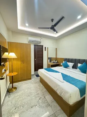 a hotel room with a large bed with blue pillows at Hotel Boss Palace in Mysore