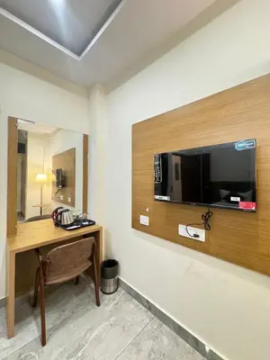 a room with a desk and a television on a wall at Hotel Boss Palace in Mysore