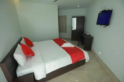 a bedroom with a bed with red pillows and a television at Premier Tourist Home in Kunnamkulam