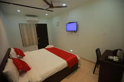a bedroom with a bed and a tv on the wall at Premier Tourist Home in Kunnamkulam