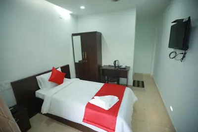 a bedroom with a bed with a red and white blanket at Premier Tourist Home in Kunnamkulam