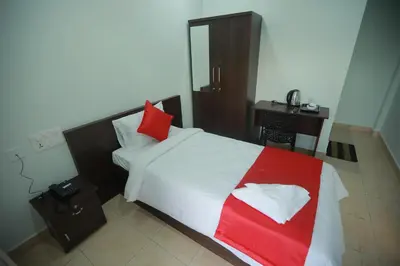 a bedroom with a white bed with red pillows and a desk at Premier Tourist Home in Kunnamkulam