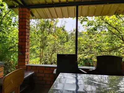 a table and chairs on a porch with a view of trees at Pear Tree Luxe Entire 3BHK Villa - Only For Family in Kotagiri