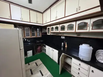 a kitchen with white cabinets and a green floor at NAS VILLA in Mysore