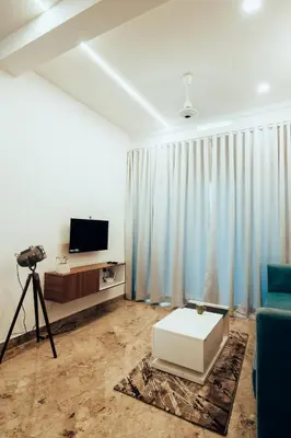 a living room with a blue couch and a television at Avalon Homes in Perintalmanna