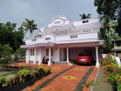 a white house with a car parked in it at COZY Homes in Nedumbassery