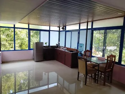 a large kitchen with a table and chairs and windows at COZY Homes in Nedumbassery