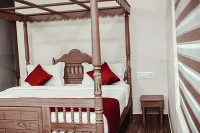 a bedroom with a four poster bed with red pillows at ATHIRAPPILY SREENILAYAM HERITAGE RESORt in Athirappilly