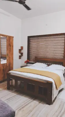 a bedroom with a large bed with a wooden headboard at UPPU HOMESTAY in Mulappilangād