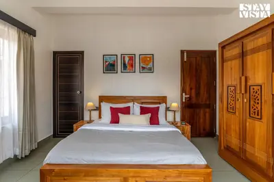 a bedroom with a large bed with red pillows at StayVista at Lagoons Villa with Lawn, Pool, WiFi in Kozhikode
