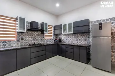 a kitchen with black cabinets and a stainless steel refrigerator at StayVista at Lagoons Villa with Lawn, Pool, WiFi in Kozhikode
