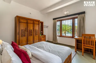 a bedroom with a bed and a desk and a window at StayVista at Lagoons Villa with Lawn, Pool, WiFi in Kozhikode