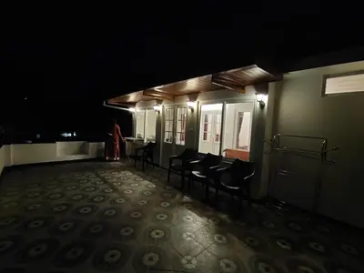 a dark hallway with chairs and a person in the background at Silver Spruce Glass Villa 1BHK Kotagiri in Kotagiri