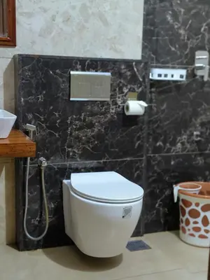 a white toilet in a bathroom with a black wall at Ananda Holiday Home in Ambalavayal