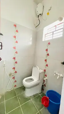 a bathroom with a toilet with flowers on the wall at White House - 2BHK - Esha Apartment in Coimbatore