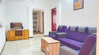 a living room with a purple couch and a tv at White House - 2BHK - Esha Apartment in Coimbatore