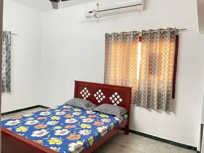 a bedroom with a bed with a blue comforter at White House - 2BHK - Esha Apartment in Coimbatore