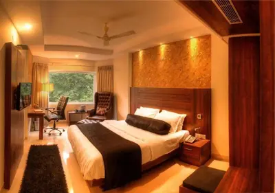a bedroom with a large bed and a desk at THE DAWN HOTEL in Mysore