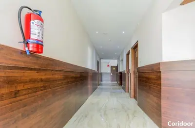 a long hallway with a fire extinguisher on the wall at THE DAWN HOTEL in Mysore