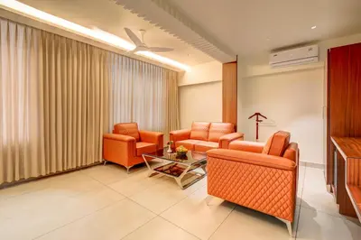 a living room with orange chairs and a piano at Hotel Hari Govindas Mysore - Explore the Heart of Mysore in Mysore