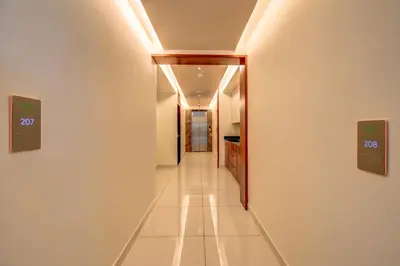 a hallway with white walls and white tile floors at Hotel Hari Govindas Mysore - Explore the Heart of Mysore in Mysore