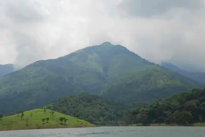 a mountain in the distance with a body of water at Century Grand Hotel in Mananthavady