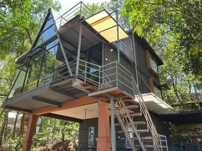 a tree house with stairs on the side of it at Wildrootstay 3 bed cottage in Pinangode