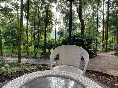 a white chair sitting in front of a table at Wildrootstay 3 bed cottage in Pinangode