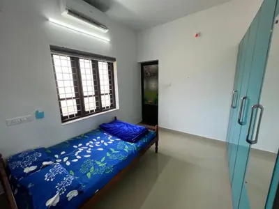 a bedroom with a bed with blue sheets and a window at Happy Villa Homestay - 2 in Chelakara