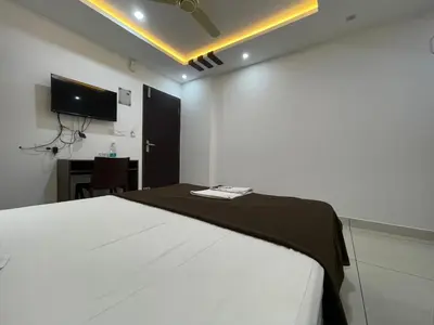 a bedroom with a bed and a desk and a television at RK Residency Calicut in Kozhikode