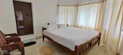 a bedroom with a bed and a window and a chair at Streaming Valley Independent Coffee Estate Stay in Madikeri