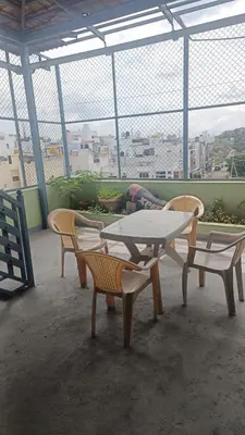 a table and chairs with a person sleeping on a balcony at AR premium family homestay in Mysore